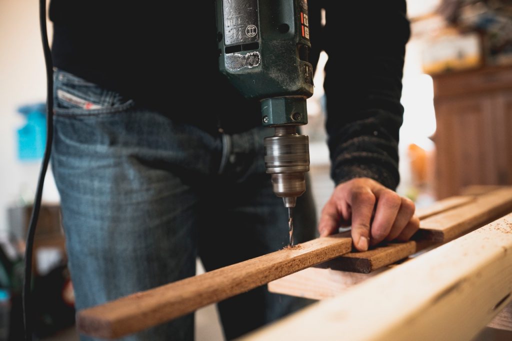 personne qui utilise une perceuse sur une planche de bois